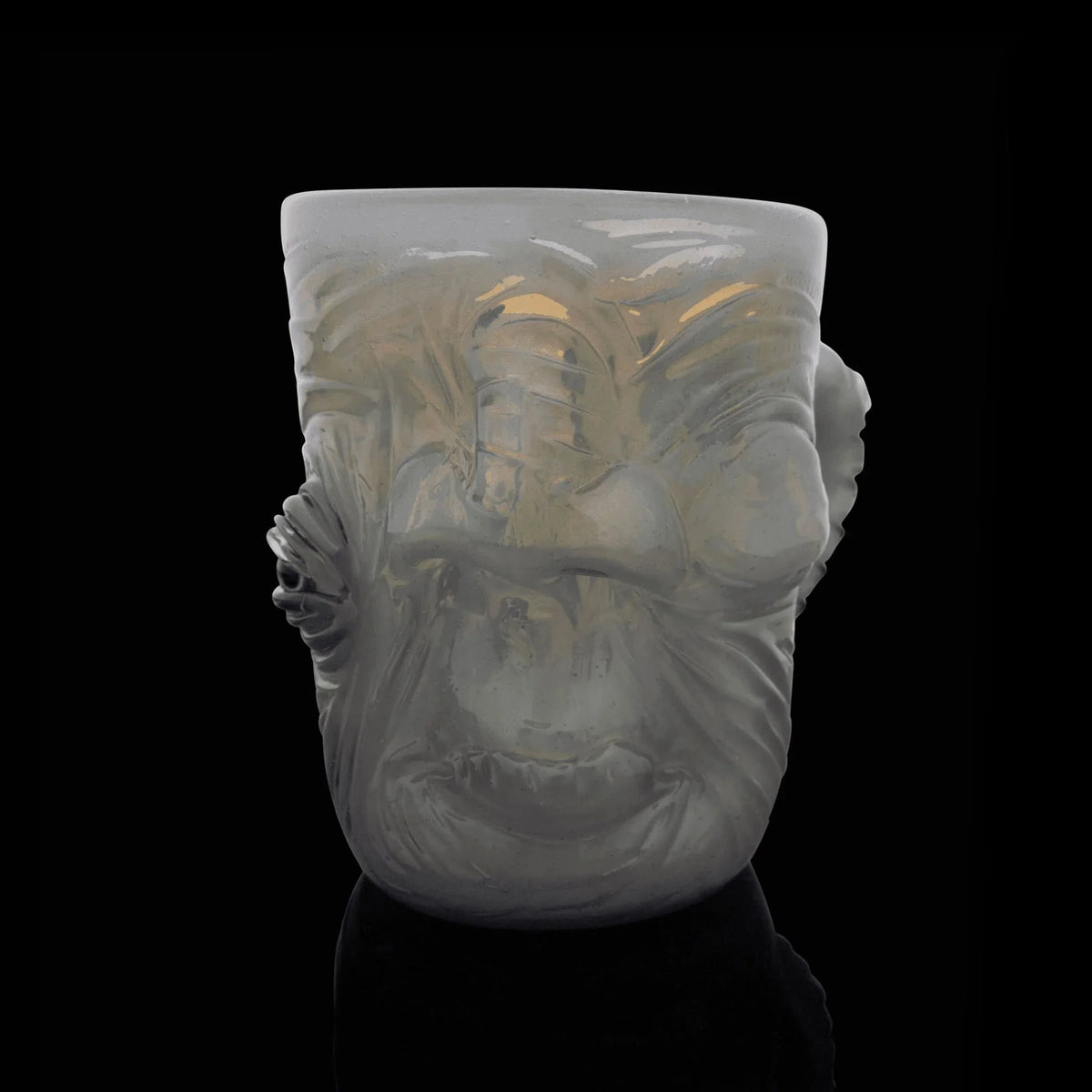 Pastel glass mug with sculpted face design, artistic drinkware on black background