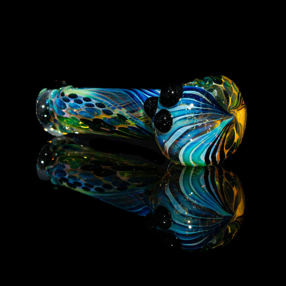 Colorful glass spoon pipe with black dots and fumed swirl design on black background