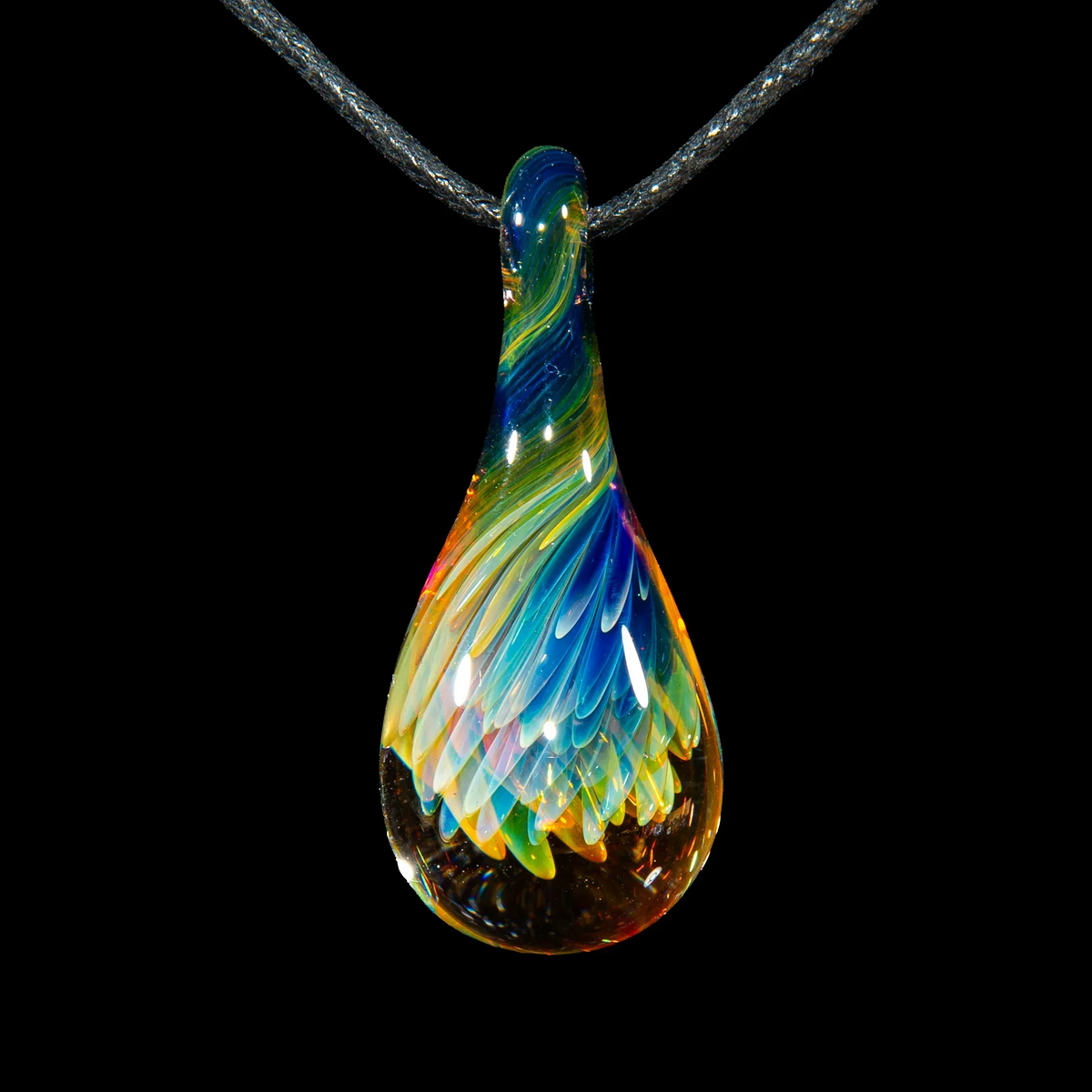 Colorful glass teardrop pendant with implosion pattern on black cord, jewelry photography