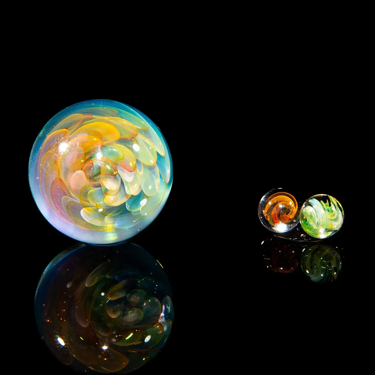 Colorful glass marble set with artistic fume implosion designs on black background