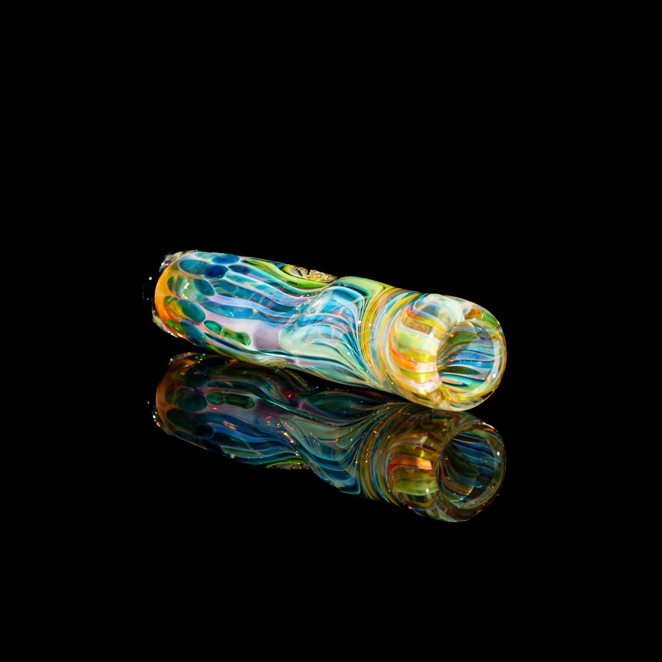 Colorful fumed glass one hitter pipe with swirled patterns on a black reflective background
