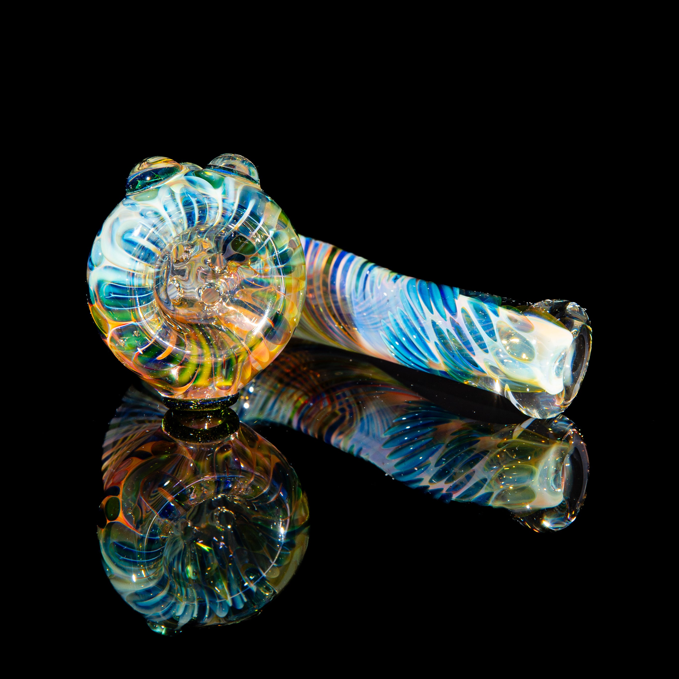 Colorful fumed glass hand pipe with swirled patterns and four holes on a black background