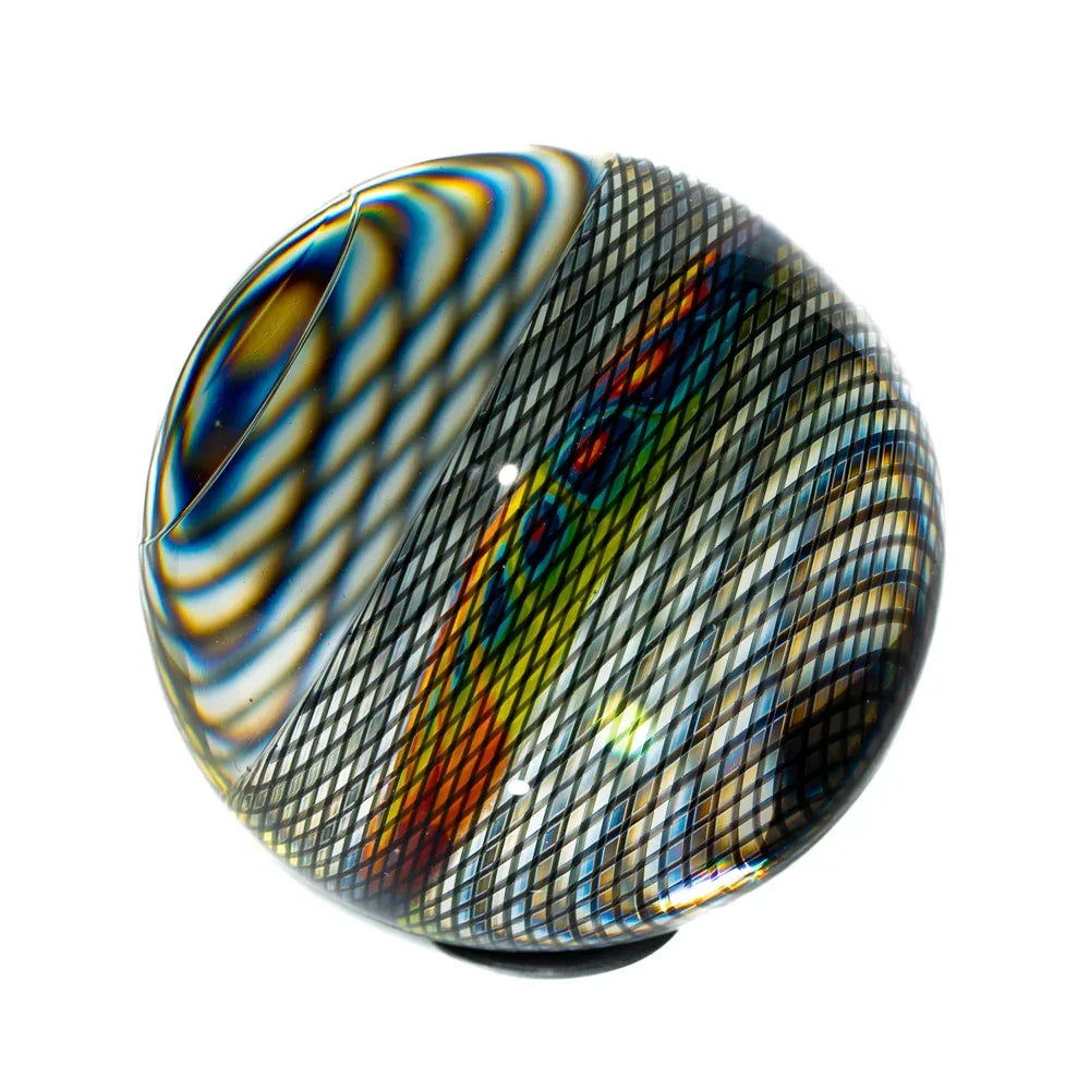 Handcrafted glass marble with rainbow slice and black reticello pattern on white background