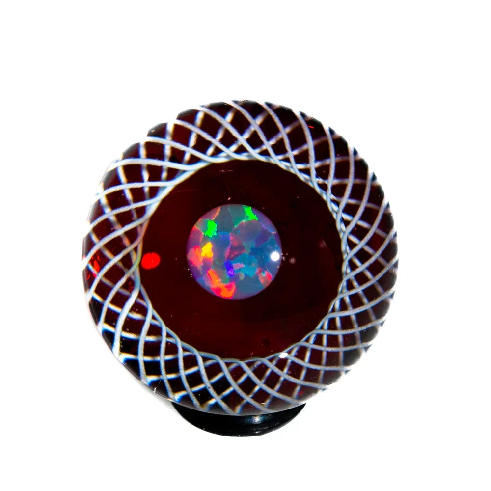 Handcrafted glass marble with red base, intricate white lattice, and a colorful opal center