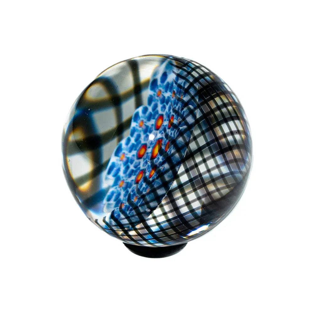 Handcrafted glass marble with blue, red, and black lattice pattern on white background