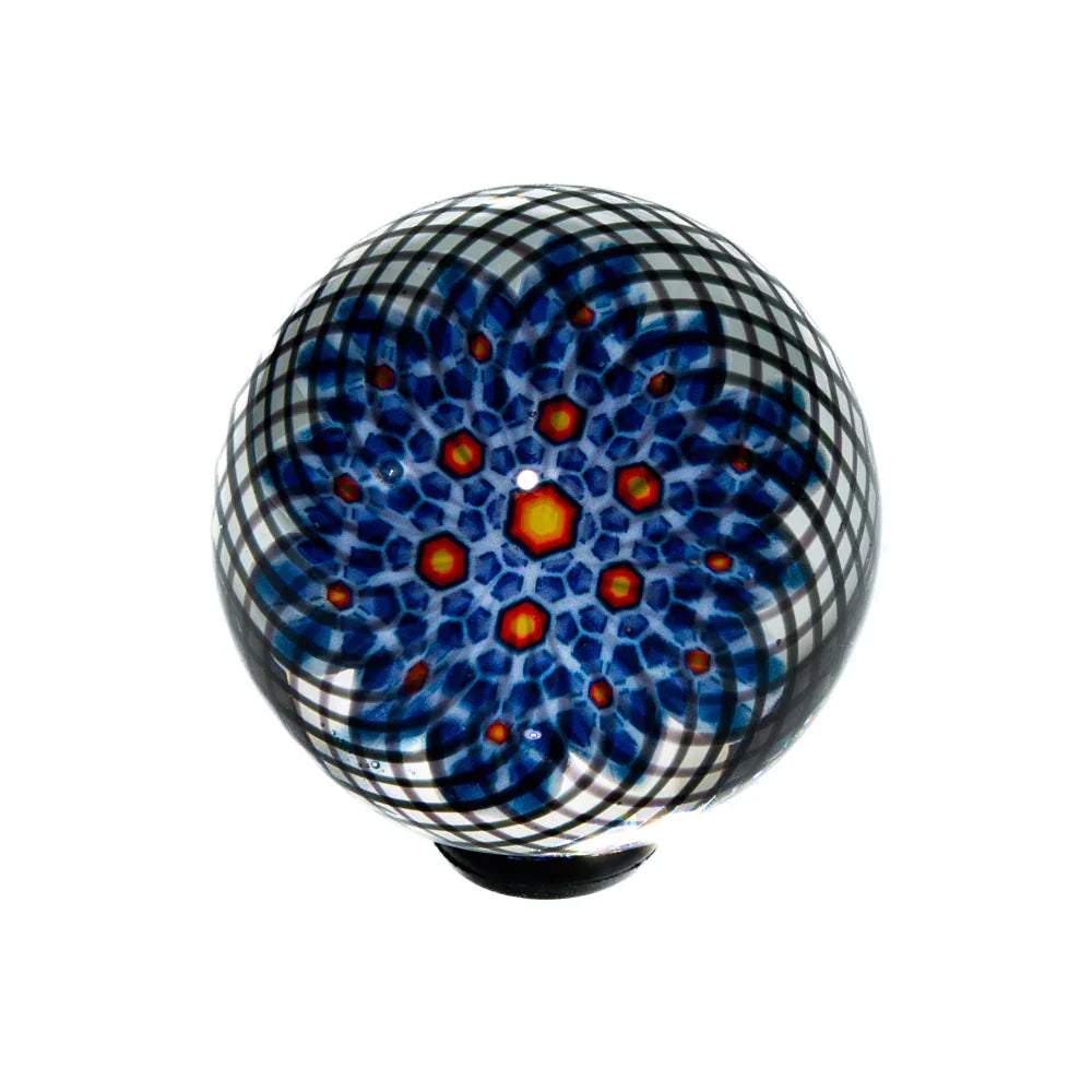 Handcrafted glass marble with intricate blue, red, and black geometric pattern on white background.