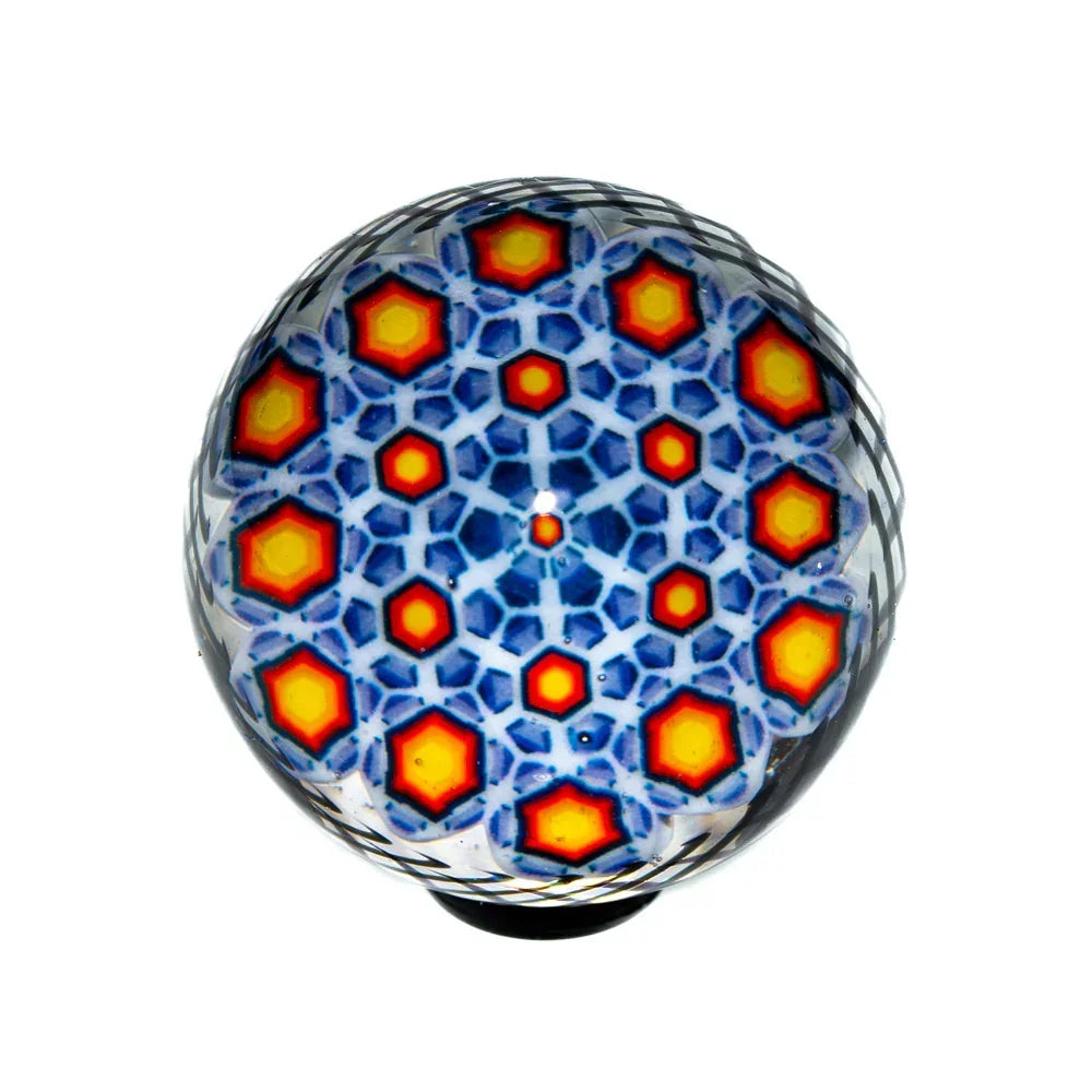 Colorful glass marble with intricate blue hex pattern and red-yellow accents, top view