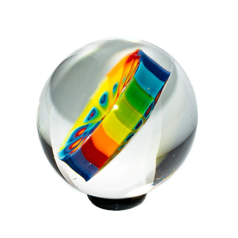 Handcrafted glass marble with rainbow millefiori design on a white background