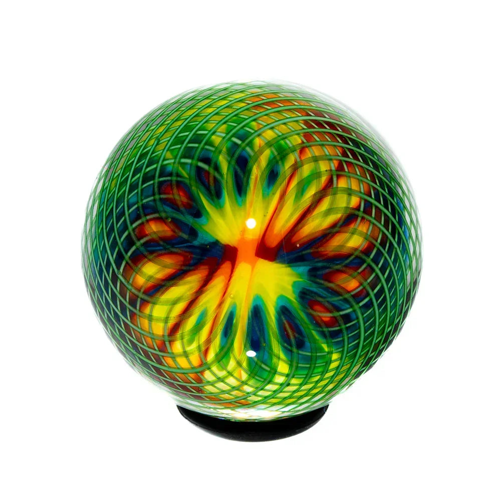 Handcrafted glass marble with rainbow colors and green lattice pattern on white background