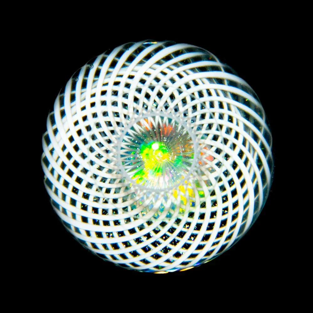 Handcrafted glass marble with white spiral lattice and colorful opal core on black background