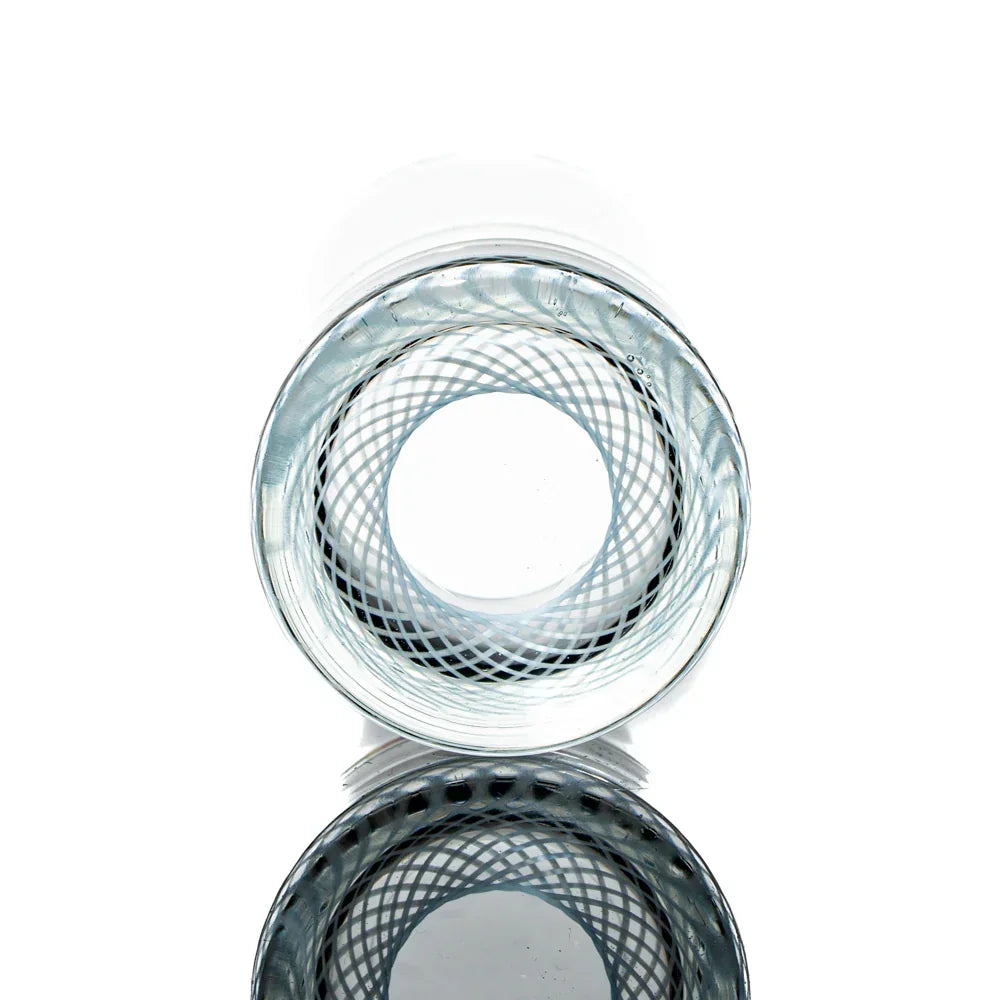 Clear glass shot glass with intricate white reticello pattern, shown on white background.