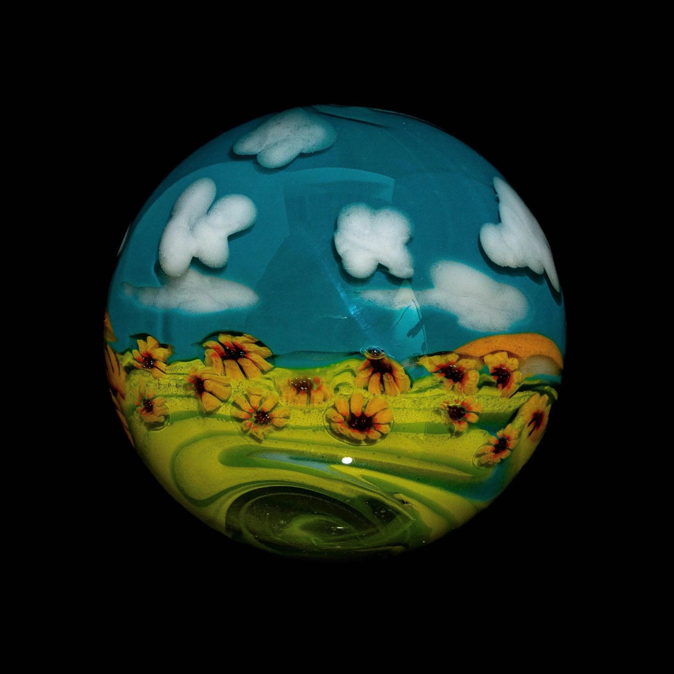 Handcrafted glass marble featuring a sunflower field and blue sky with clouds design.