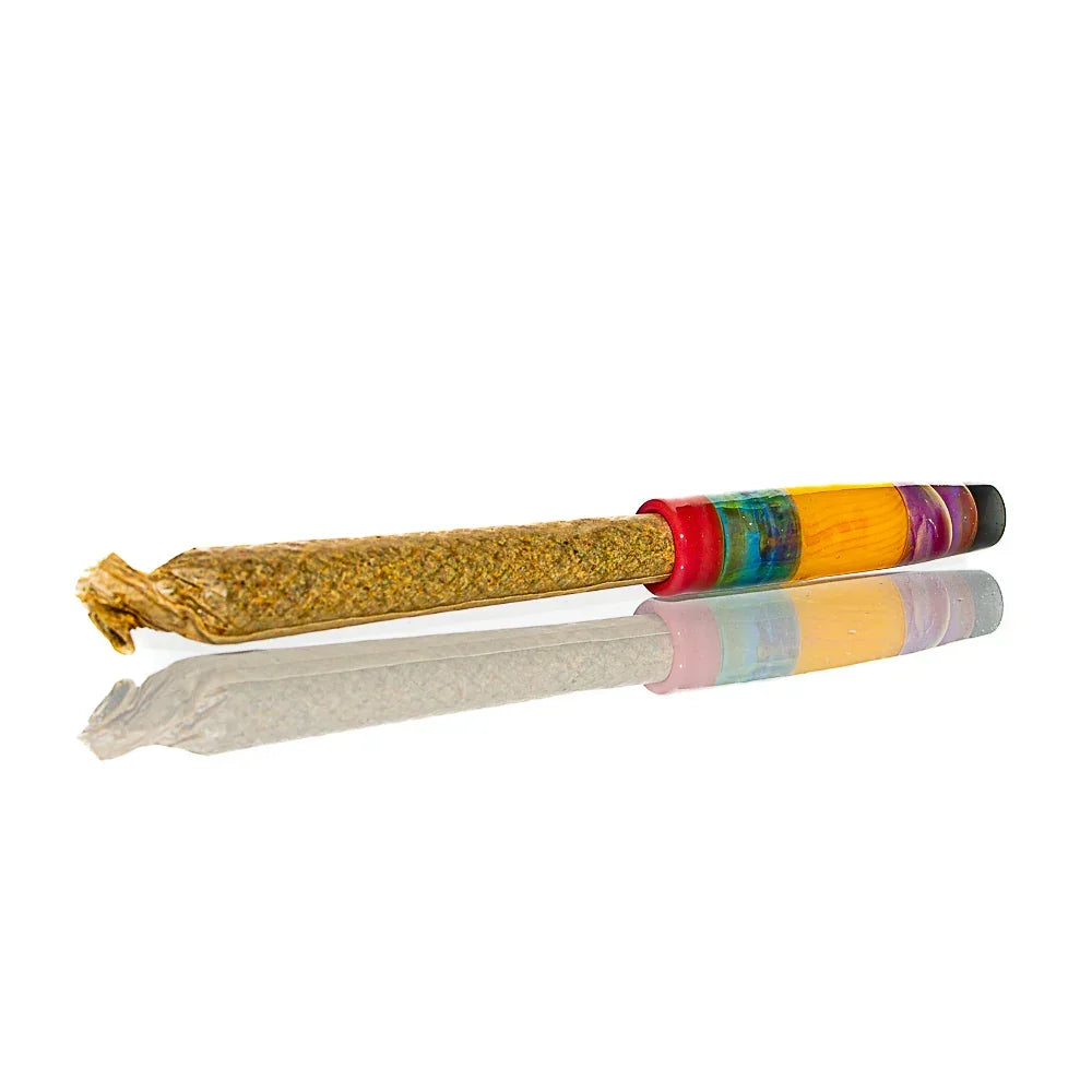 Hand-rolled herbal joint with vibrant, multicolored glass tip on white background.