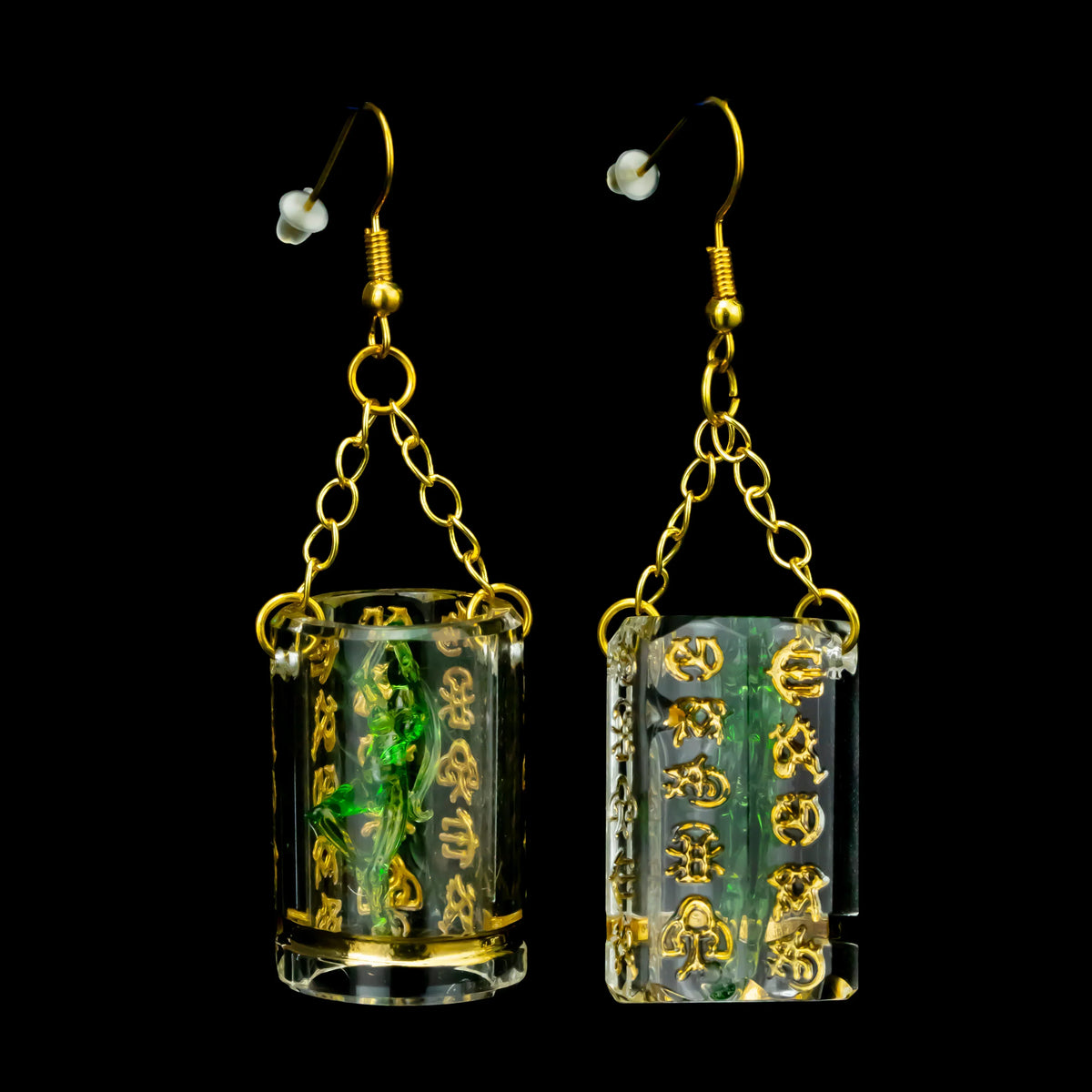 Green and gold glass earrings with chain hooks and intricate script design on black background