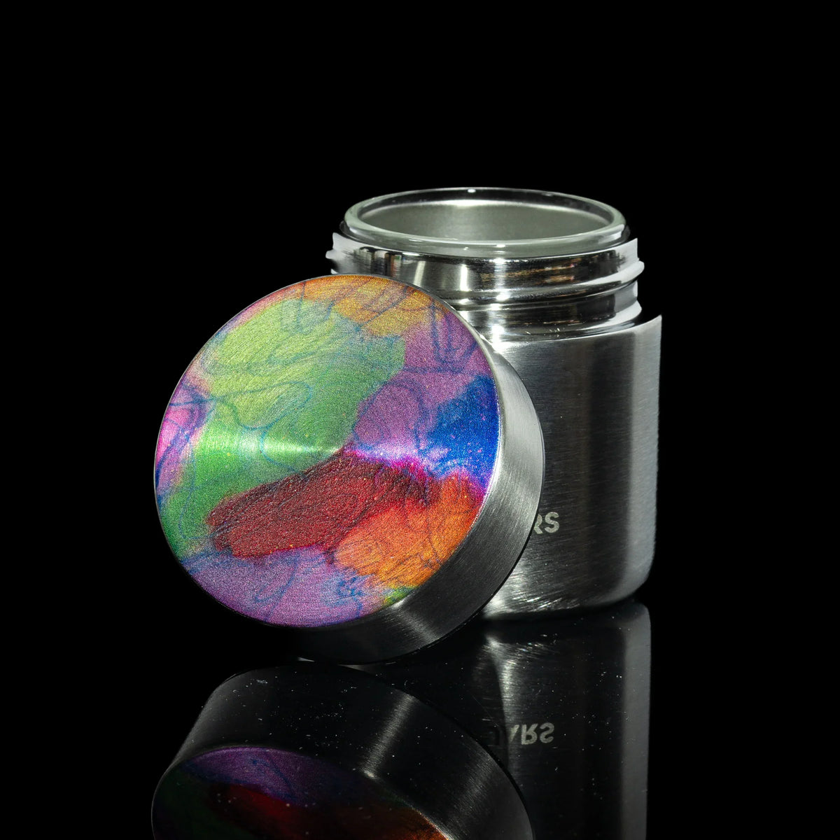 Stainless steel stash jar with a colorful, tie-dye patterned lid on a black background