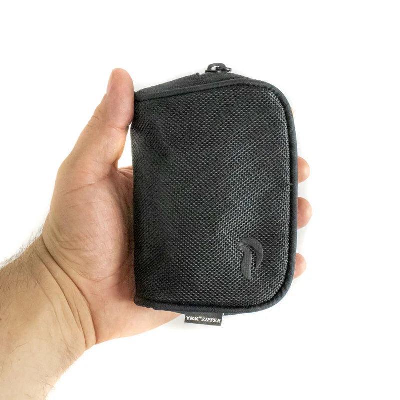 Hand holding a small black textured zippered carrying case with subtle logo