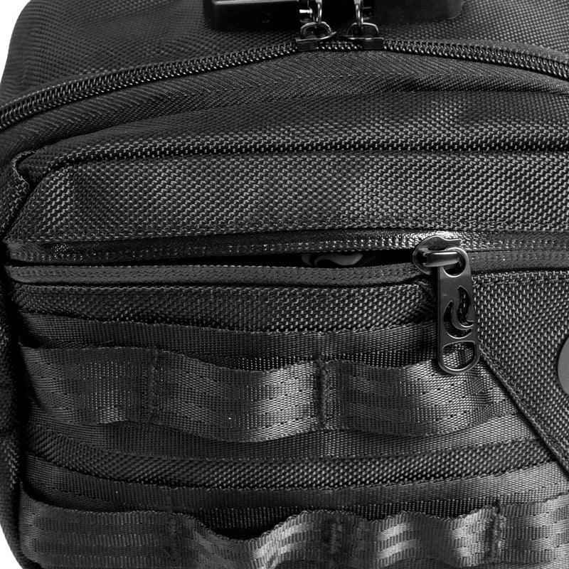 Close-up of a black textured backpack pocket with zipper and utility webbing.