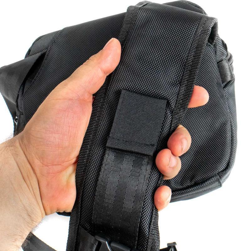 Hand holding a durable black nylon shoulder strap on a padded bag