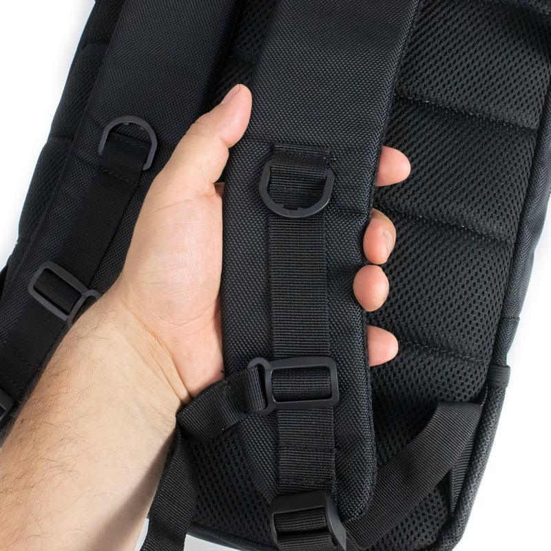 Hand holding black backpack straps with padded mesh back and adjustable buckles