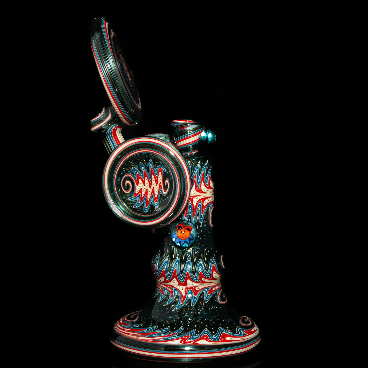 Colorful heady glass rig with red, blue, and white intricate patterns on black background