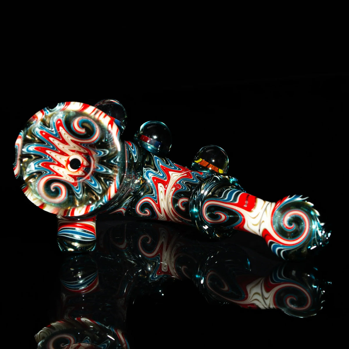 Colorful hand-blown glass pipe with red, blue, and white swirl patterns on black background.