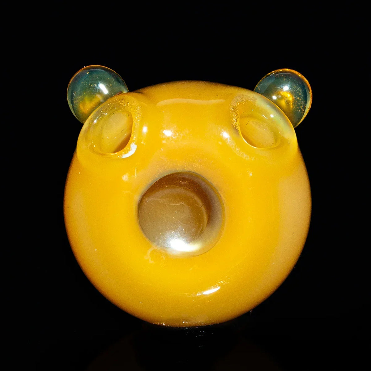 Yellow glass bear carb cap with round mouth and clear ears on a black background