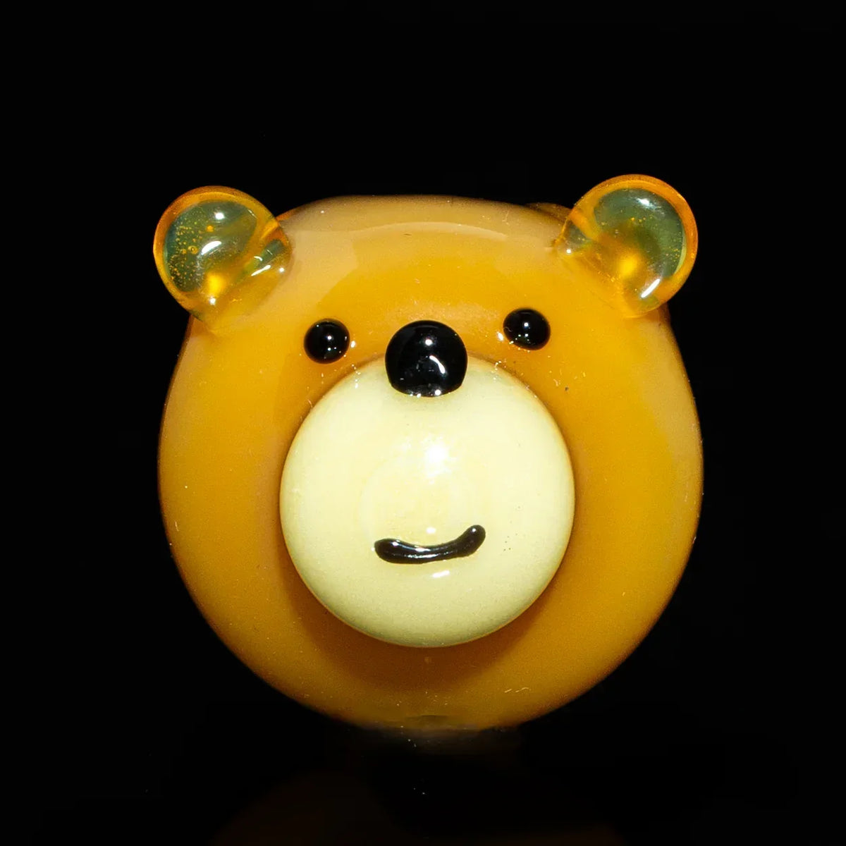 Brown glass bear carb cap with a smiling face on a black background