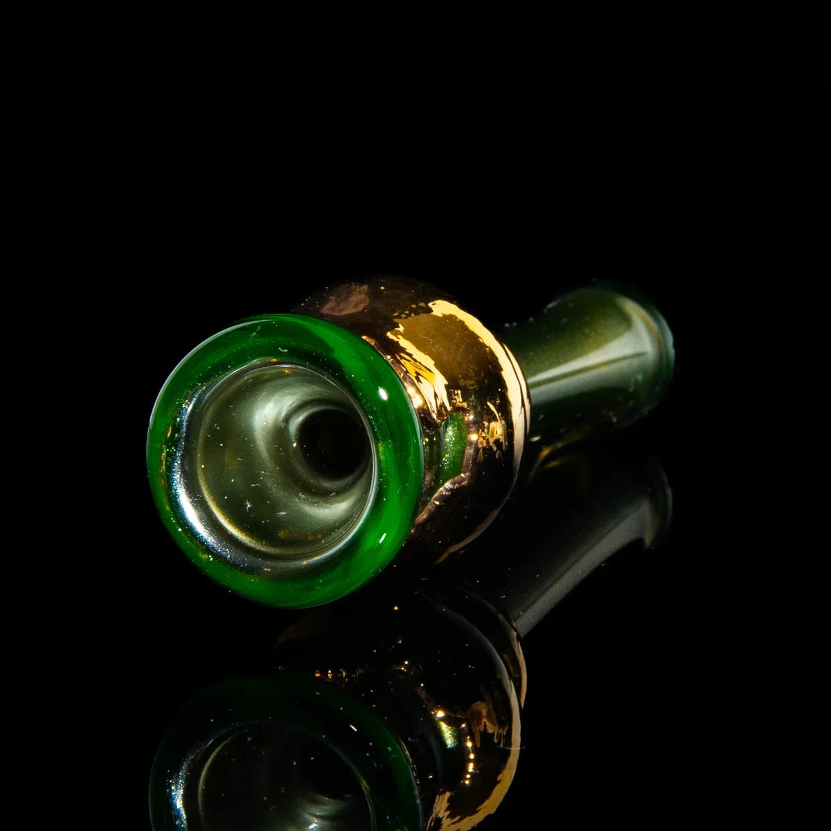 Electrum gold glass chillum pipe with green rim on black reflective surface