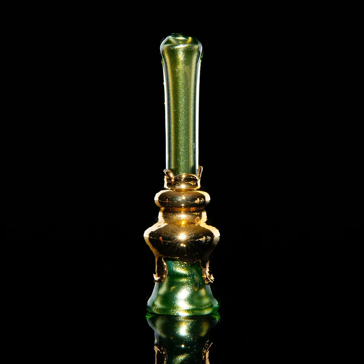 Gold and green glass chillum pipe with reflective finish on a black background