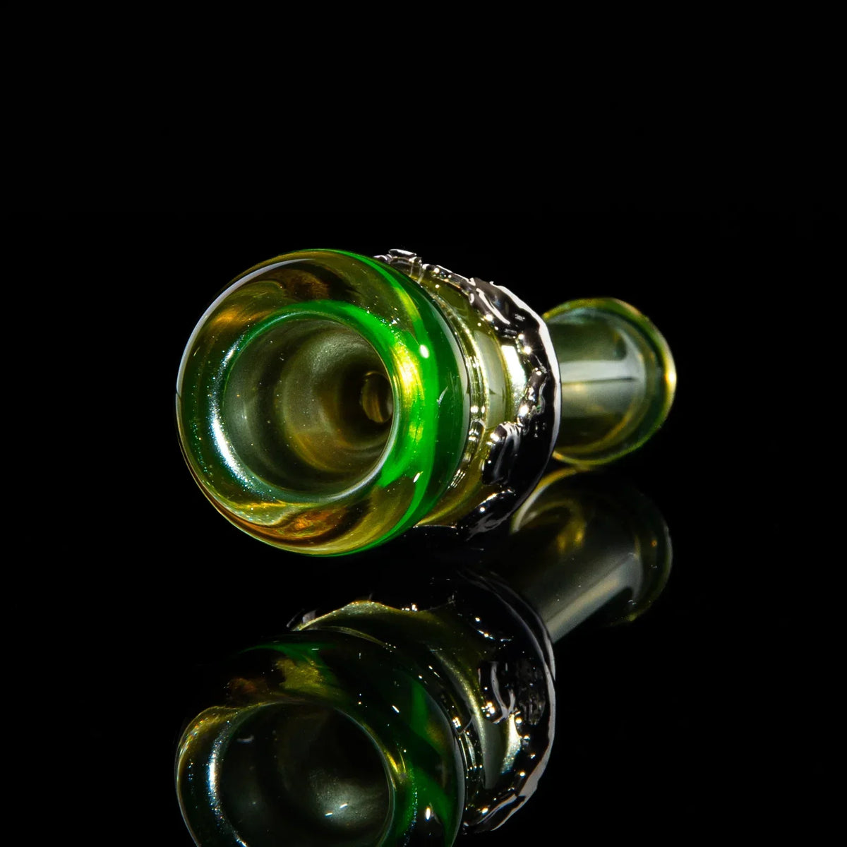 Green and yellow glass chillum with metallic accent on black reflective surface