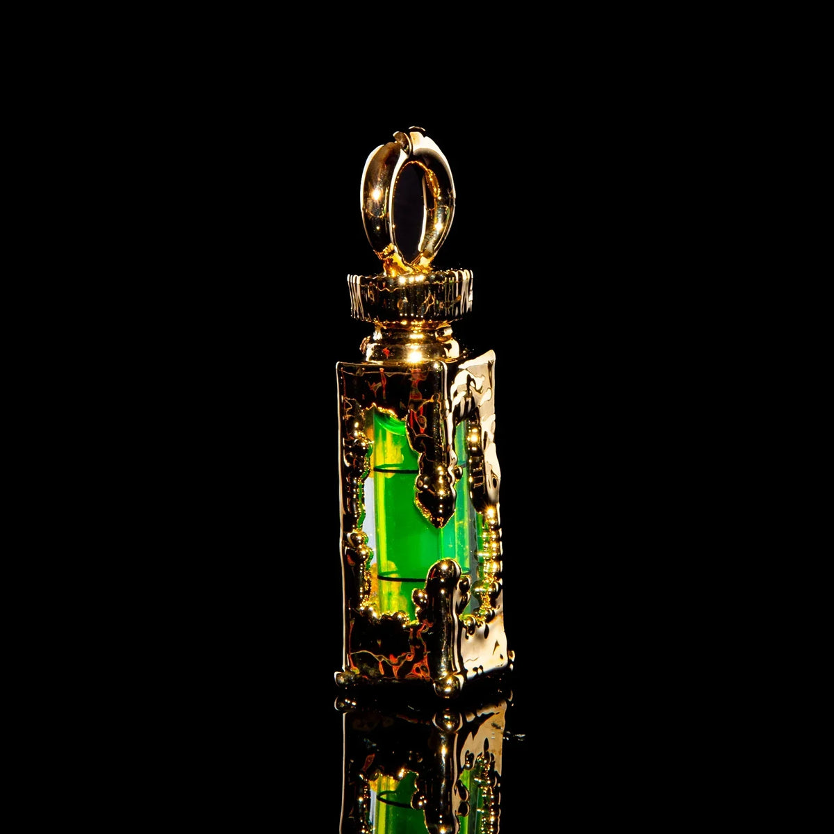 Gold pendant with intricate metalwork and glowing green glass core on black background