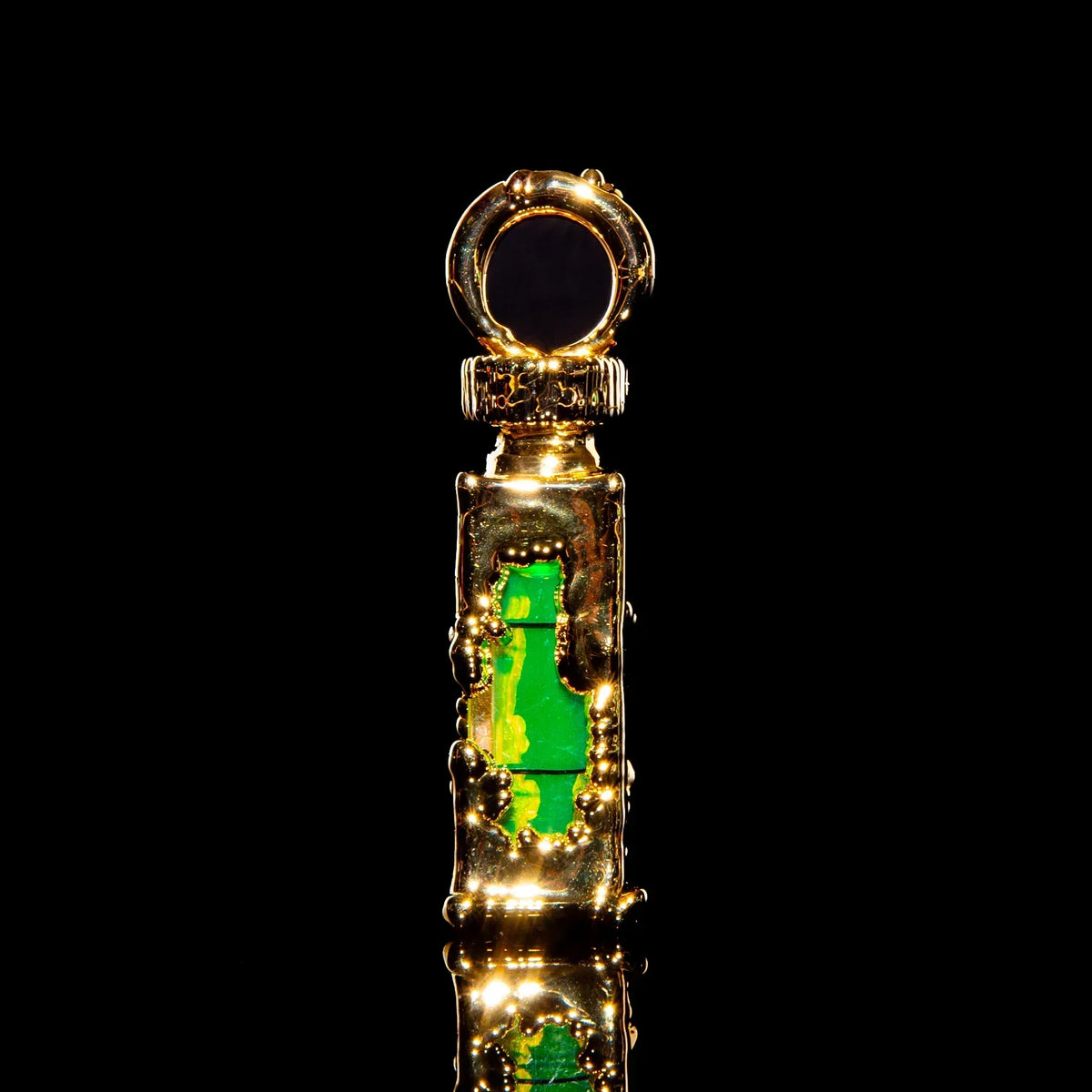 Gold glass pendant with green accents and textured details on a black background