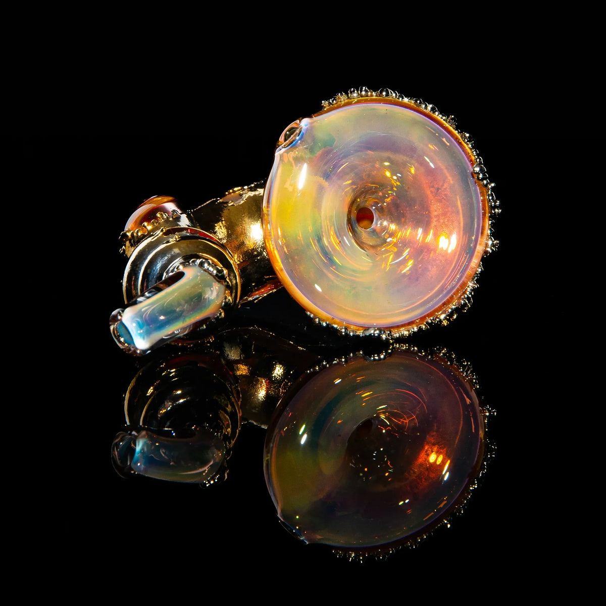 Iridescent gold glass sherlock pipe with textured details on a black reflective surface.