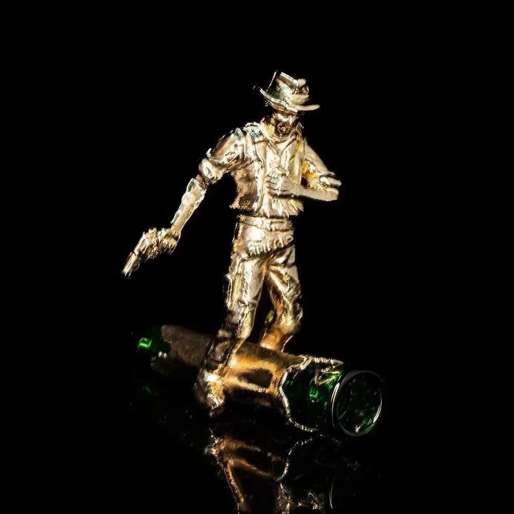 Gold cowboy figurine with revolver on artistic glass piece against black background