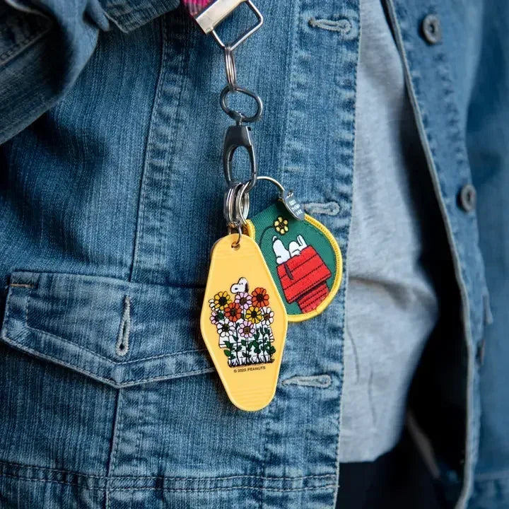 Snoopy doghouse and flower patch keychains on a denim jacket