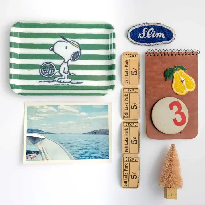 Vintage-style tray with Snoopy tennis design, green stripes, surrounded by retro collectibles.
