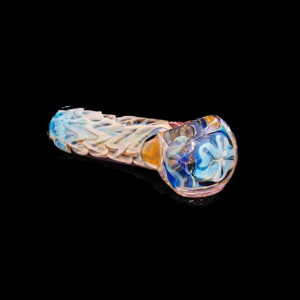Hand-blown glass spoon pipe with pink accents and blue floral design on a black background