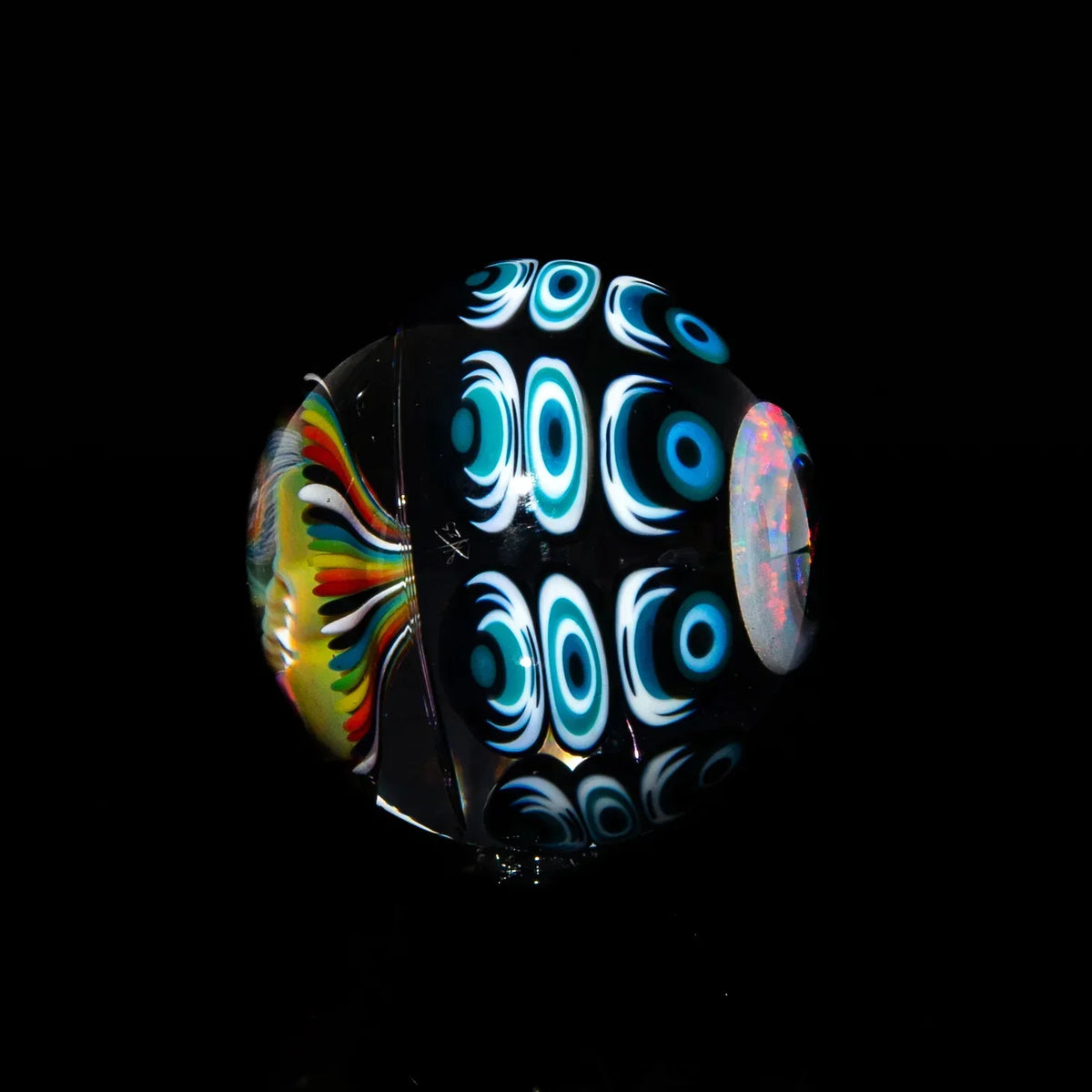 Hand-blown glass marble with blue eye pattern and colorful swirls on black background