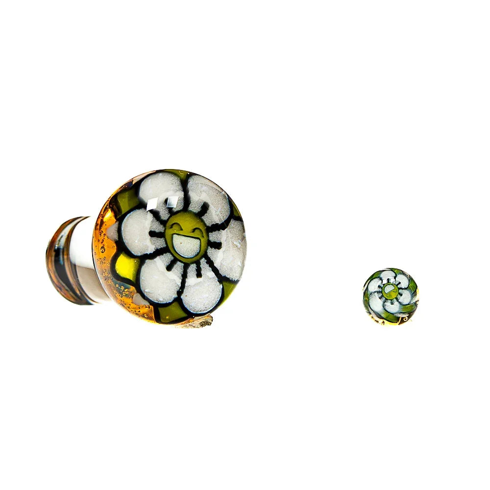 Handblown glass carb cap with happy flower design and matching terp pearl on white background.