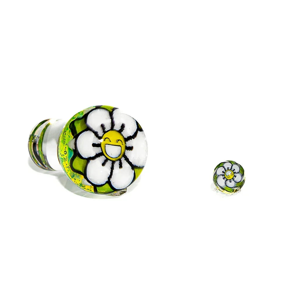 Handcrafted glass carb cap with a smiling flower design and matching pearl on white background