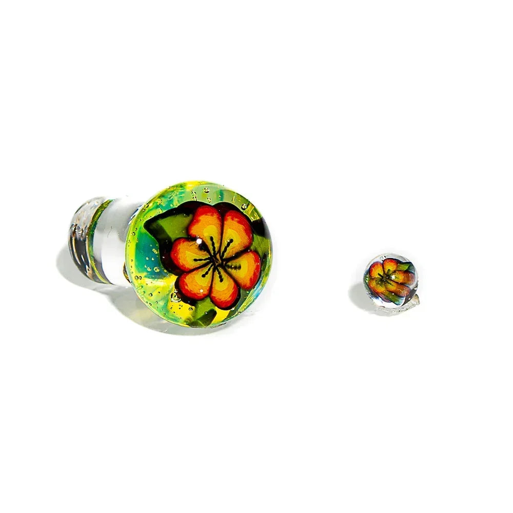 Handcrafted glass carb cap with colorful hibiscus flower design and matching accessory on white background