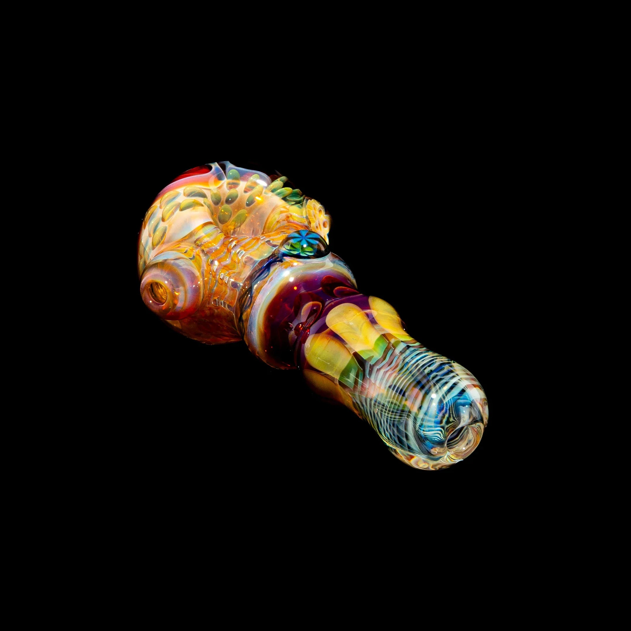Colorful hand-blown glass spoon pipe with intricate ribbon cane and fume designs on black background.