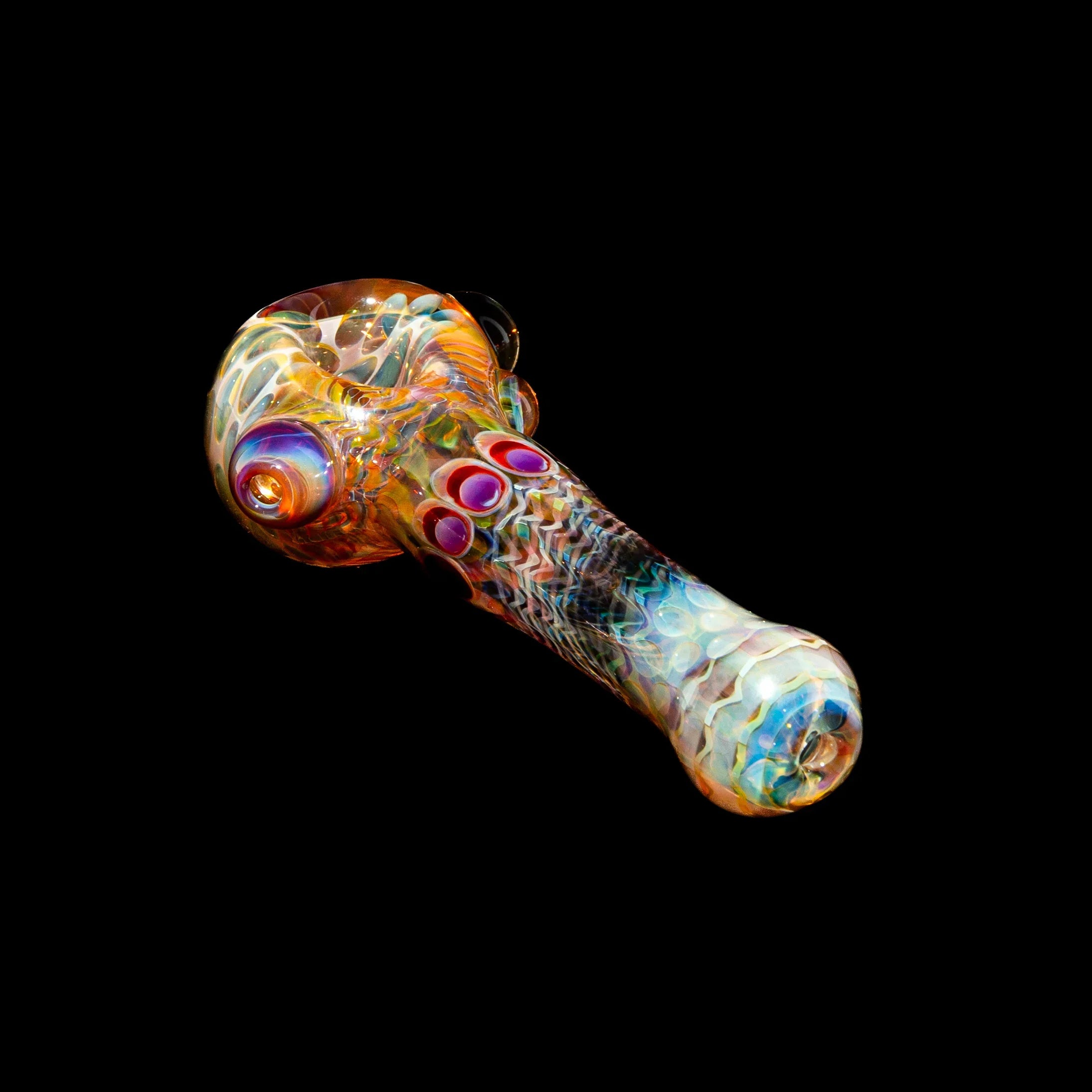 Hand-blown glass spoon pipe with honeycomb pattern and amber purple dots on black background.