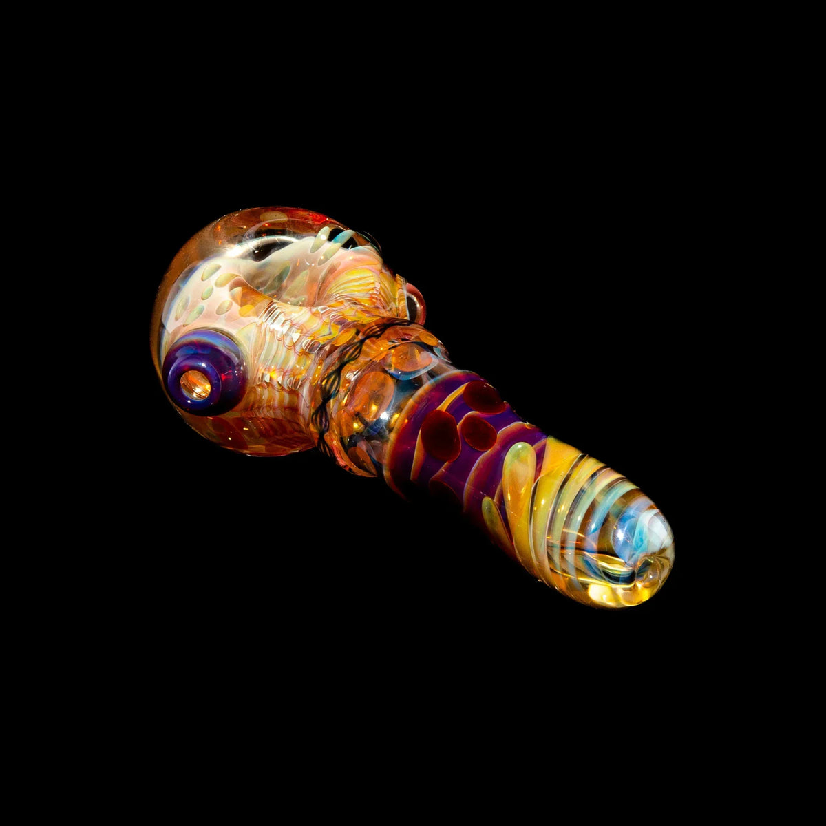 Colorful glass spoon pipe with honeycomb and ribbon cane patterns on black background