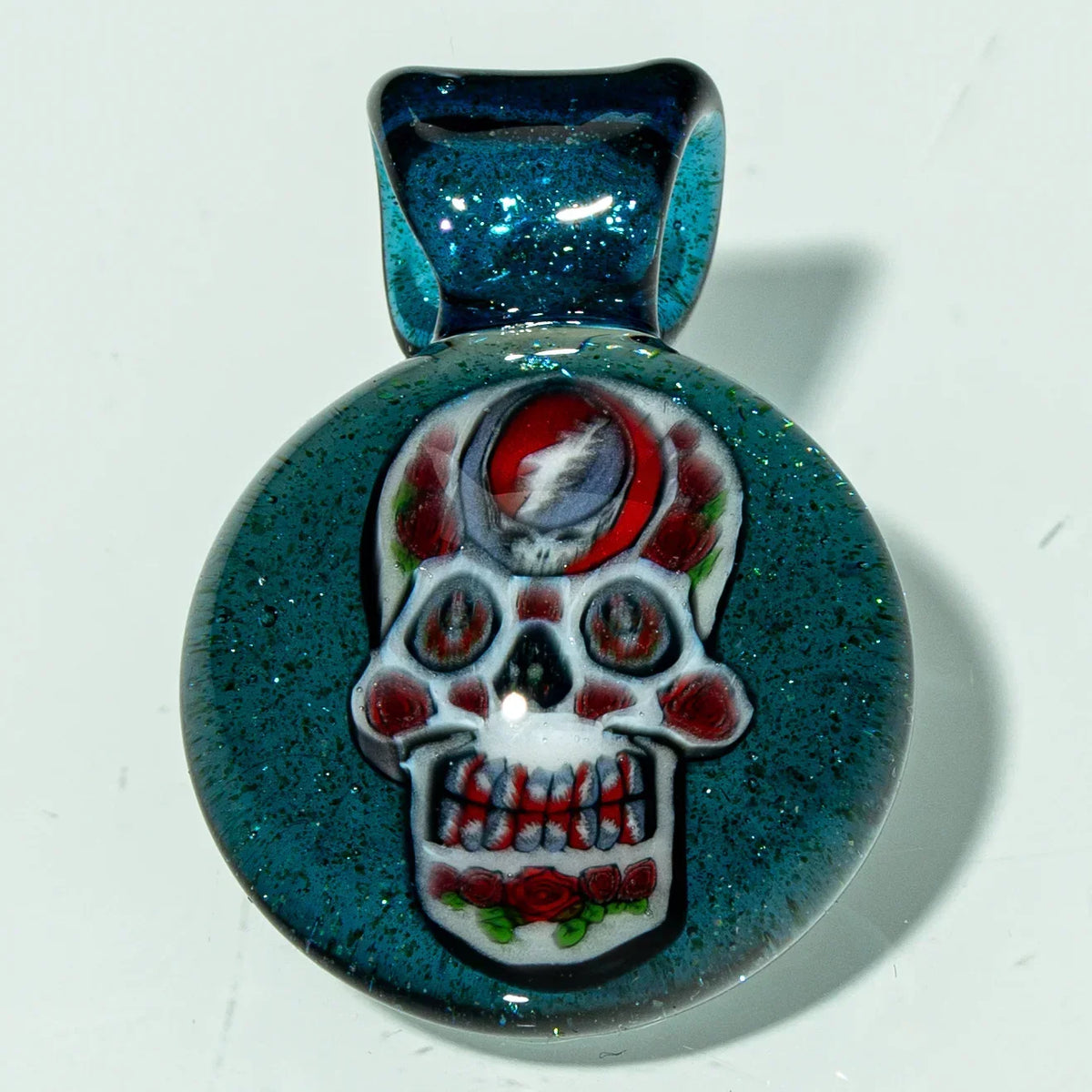 Handmade glass pendant with glittery blue background and skull design with red accents