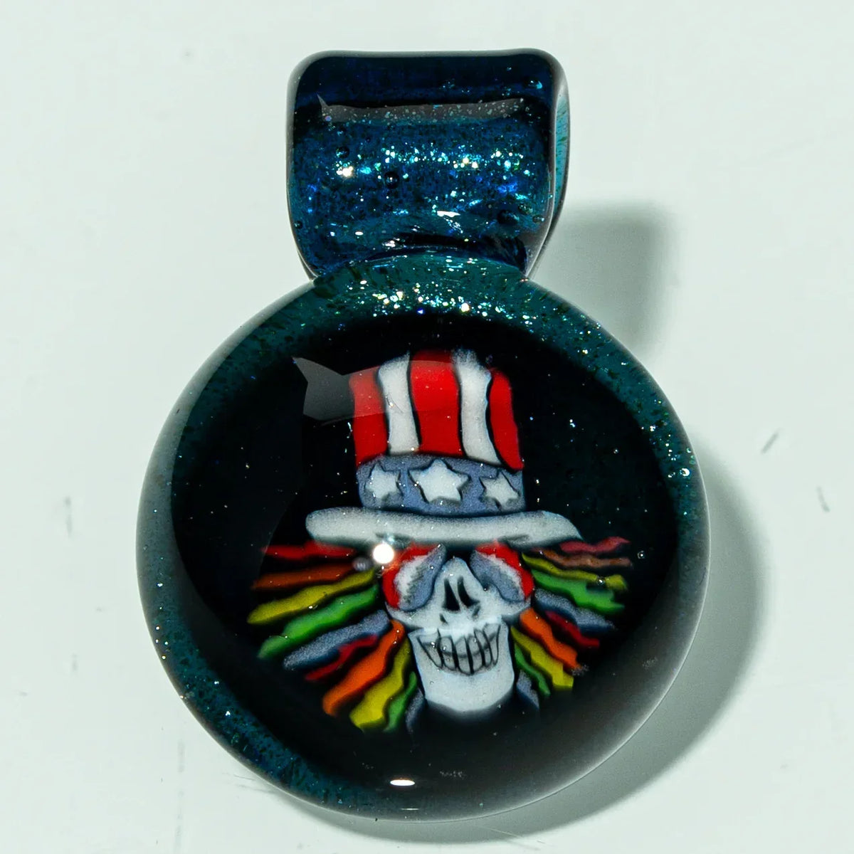 Glass pendant featuring a skull with rainbow hair and a red, white, and blue top hat