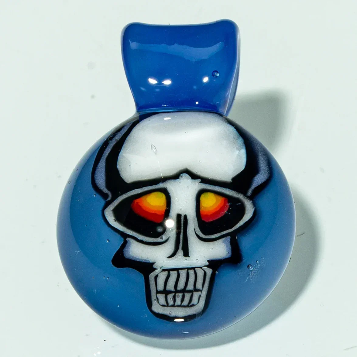 Blue glass pendant with a skull design and vibrant orange-red eyes