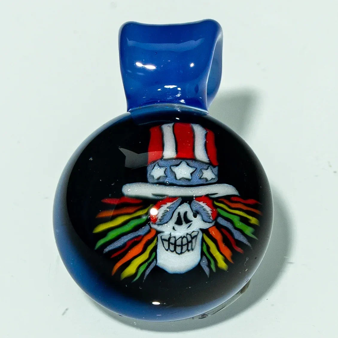 Colorful glass pendant featuring a skull with rainbow hair and a red, white, and blue hat