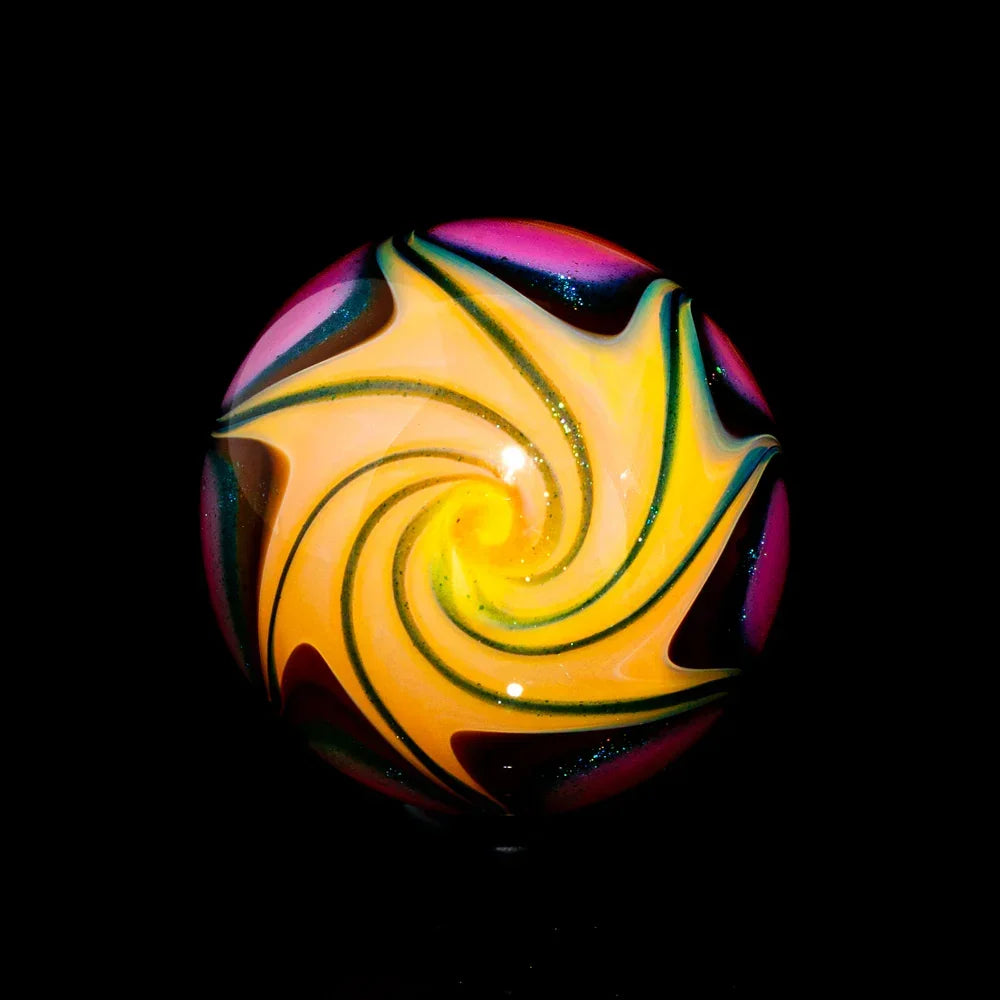 Colorful glass marble with yellow and pink spiral pattern on a black background