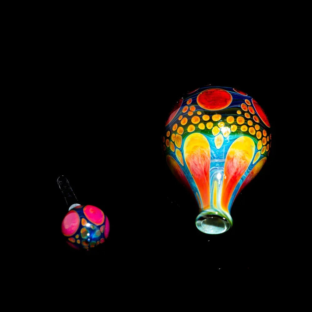 Colorful heady glass carb cap and dabber with vibrant dot and swirl patterns on black background
